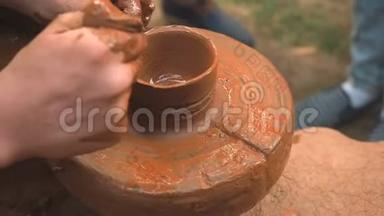 旋转陶工`的车轮和粘土器皿从上面。 一只手在陶工的车轮上用泥杯雕刻`